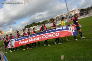 I calciatori della Torres con lo striscione di incoraggiamento per il loro ex allenatore Vincenzo Cosco (foto sito ufficiale Torres)